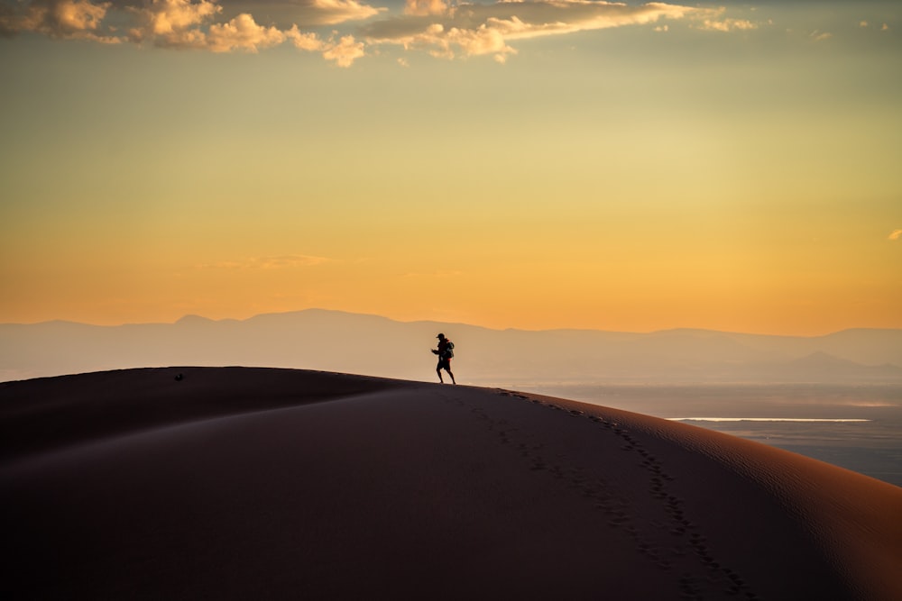 a person standing on top of a sand dune