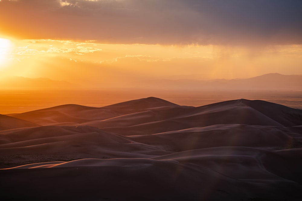 the sun is setting over the sand dunes