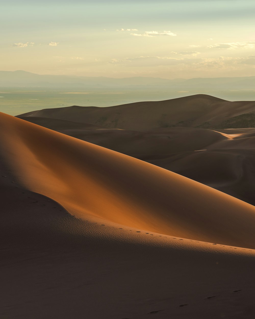 a desert with sand dunes and mountains in the background