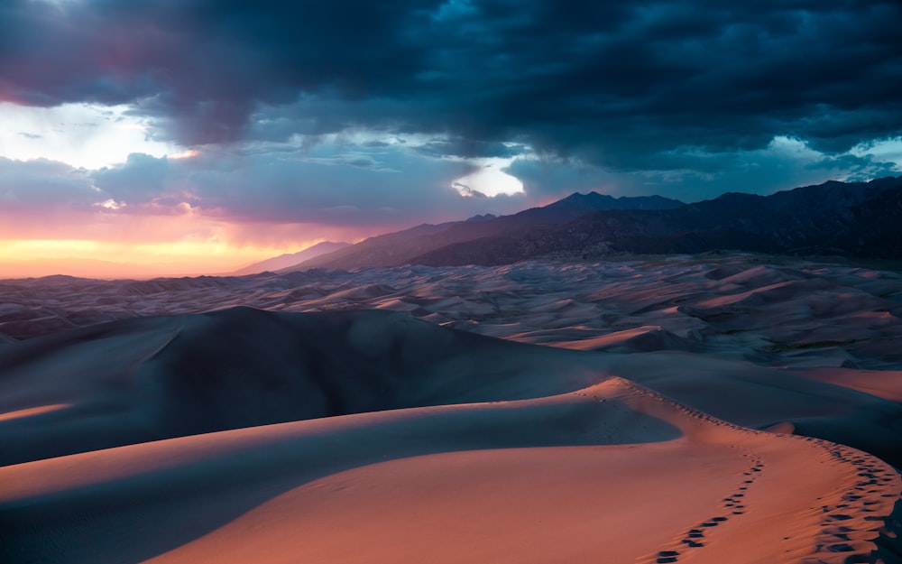 the sun is setting over the sand dunes