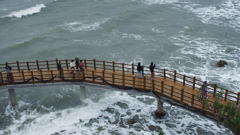 a group of people walking across a wooden bridge over a body of water