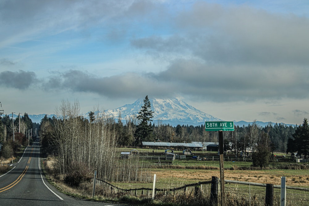 a road with a street sign and a mountain in the background