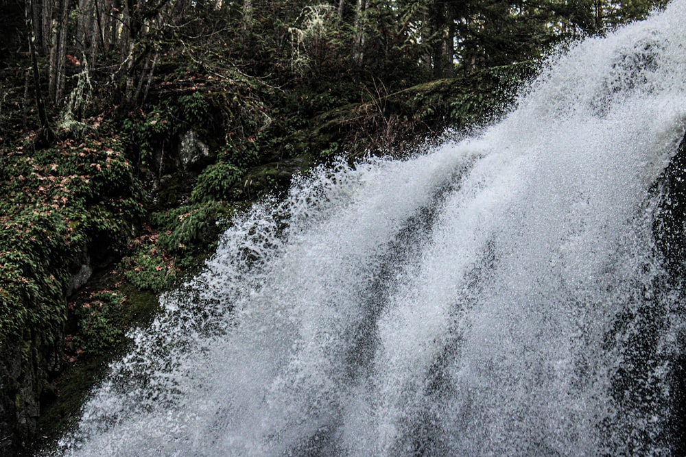 a man riding a surfboard on top of a waterfall