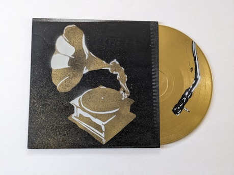 A stylized image of a gramophone painted in shades of gold and white against a dark background. Beside it, a golden vinyl record with a stylized black snake design is partially visible.