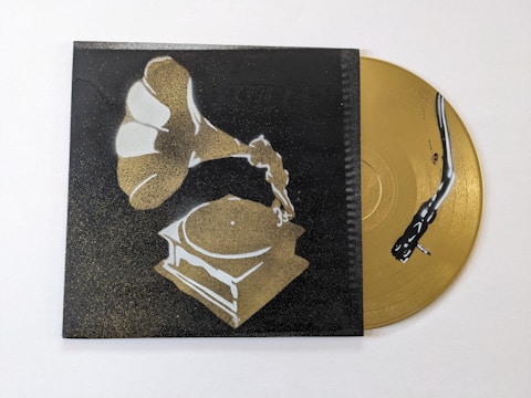 A stylized image of a gramophone painted in shades of gold and white against a dark background. Beside it, a golden vinyl record with a stylized black snake design is partially visible.
