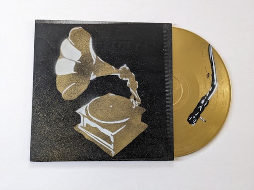 A stylized image of a gramophone painted in shades of gold and white against a dark background. Beside it, a golden vinyl record with a stylized black snake design is partially visible.