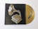 A stylized image of a gramophone painted in shades of gold and white against a dark background. Beside it, a golden vinyl record with a stylized black snake design is partially visible.