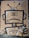A paper bag features a stylized drawing of a robot holding a spray can. The robot has a large rectangular head with a barcode on its face and two antennae on top. The bag also includes QR codes and recyclable information printed at the top.