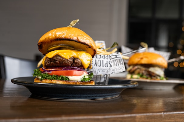 A juicy burger stacked high with melted cheese, fresh lettuce, and tomato, wrapped in a soft bun, with a side of golden fries.
