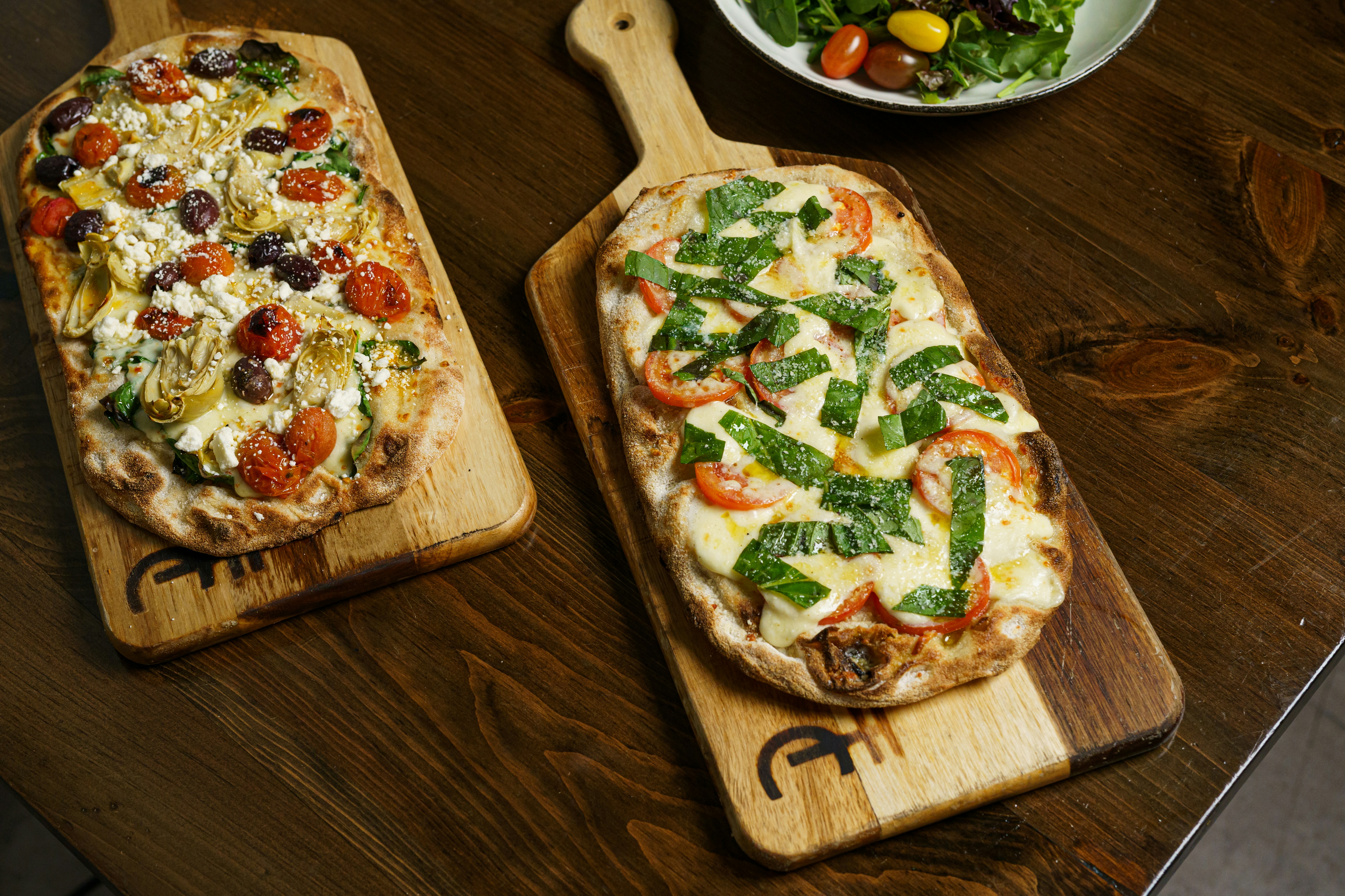 a couple of pizzas sitting on top of wooden cutting boards