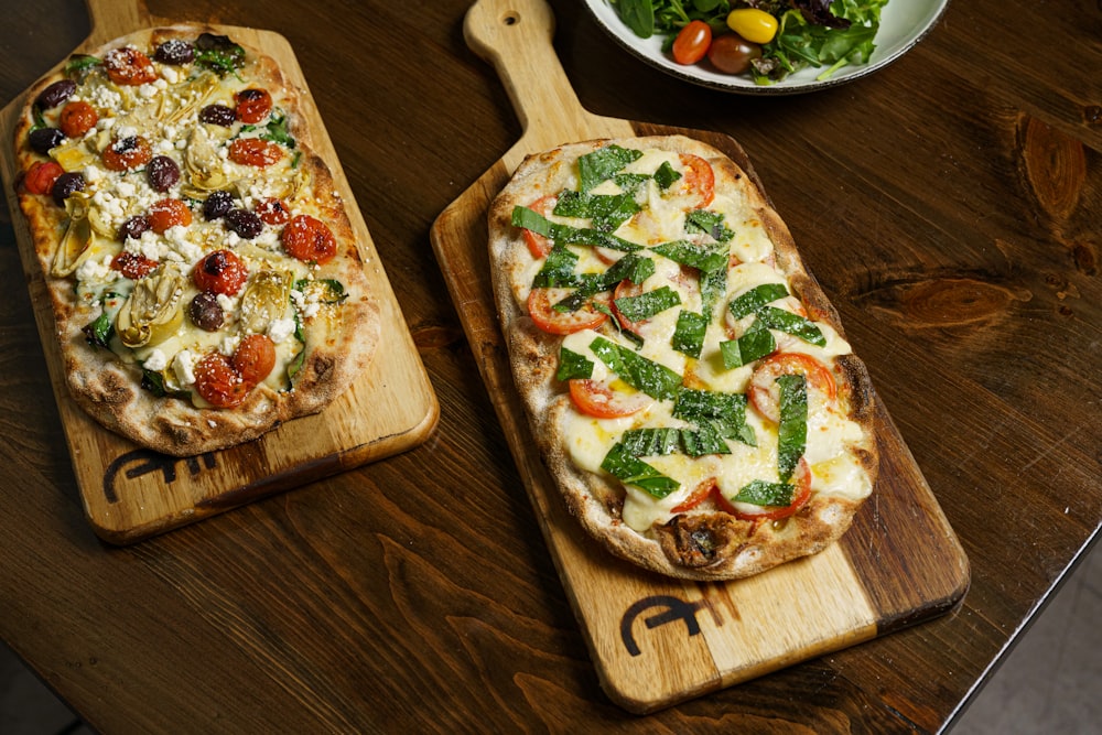 a couple of pizzas sitting on top of wooden cutting boards