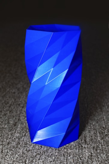 A vibrant 3D-printed geometric vase with intricate patterns on a wooden table.