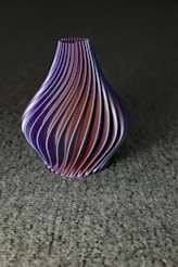 a purple vase sitting on top of a gray floor