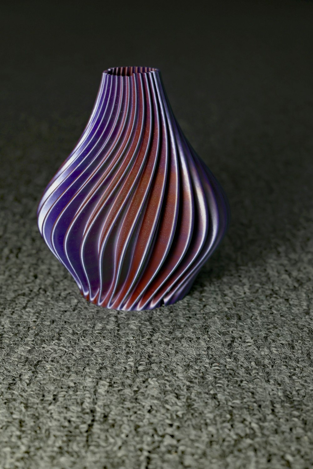 un jarrón púrpura sentado sobre un piso gris