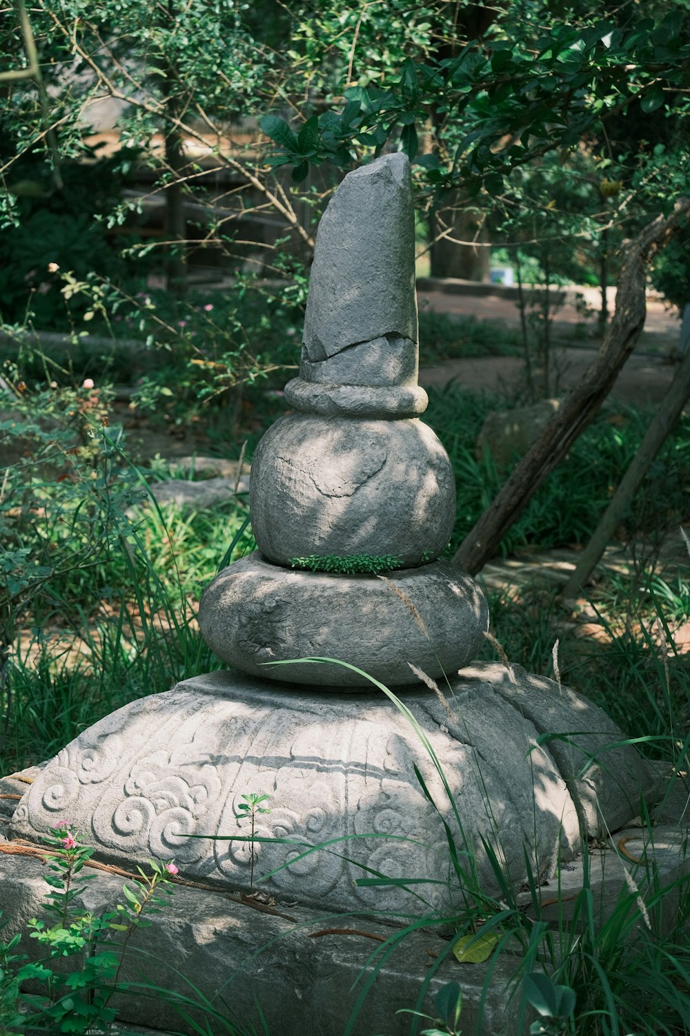 a stone statue sitting in the middle of a forest