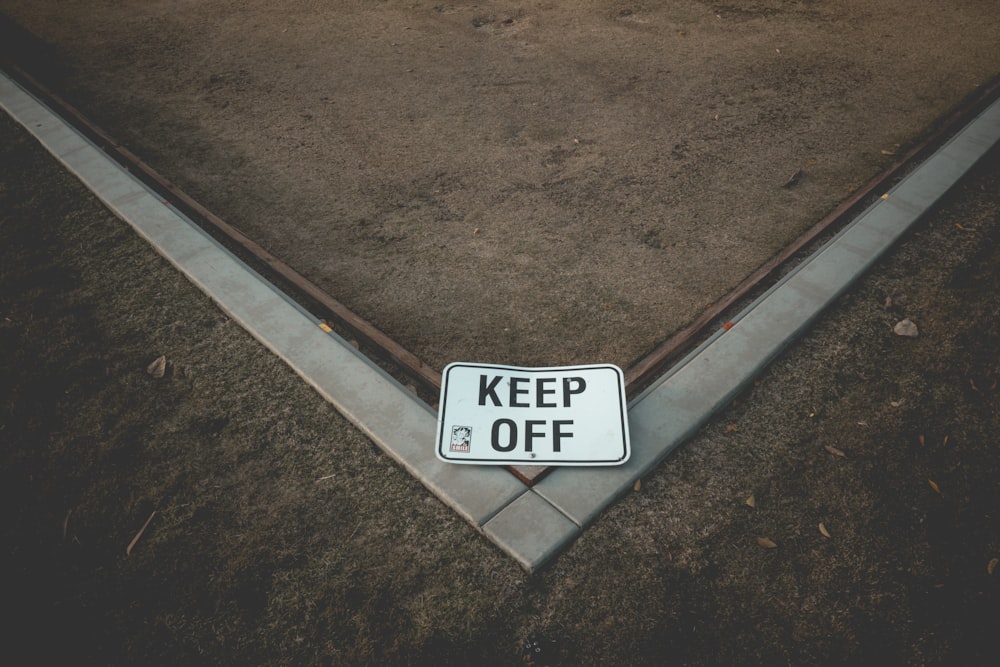 a keep off sign laying on the ground