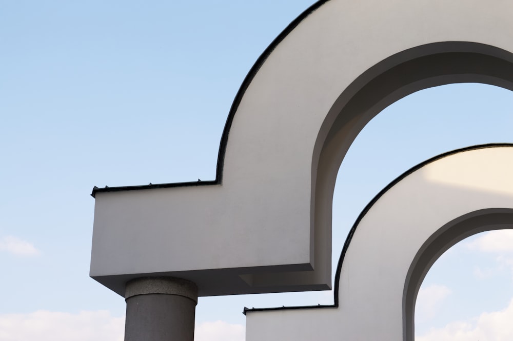 a large white arch with a sky in the background