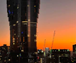 Modern financial district skyline at dusk with red hues reflecting on glass buildings.
