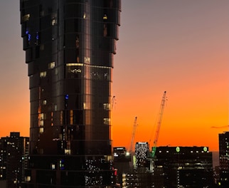 A sleek modern Dubai skyline at sunset highlighting new construction cranes and luxury towers.