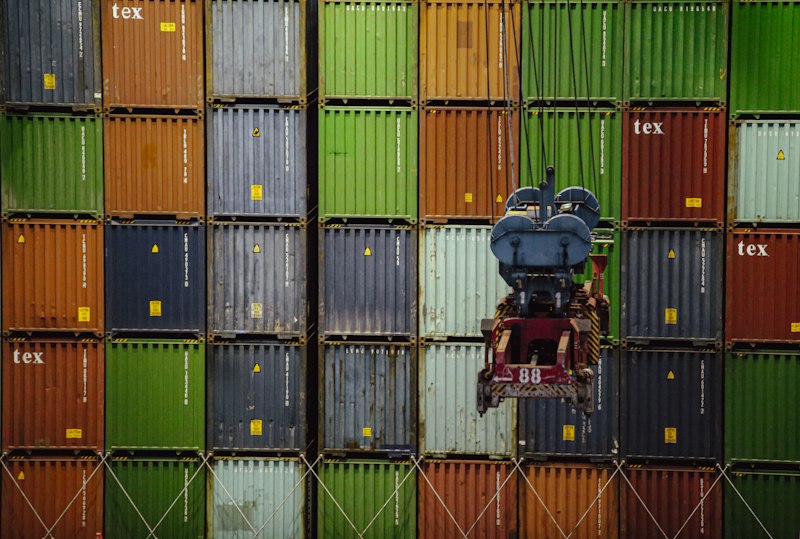 Stacked multicoloured shipping containers beneath a crane