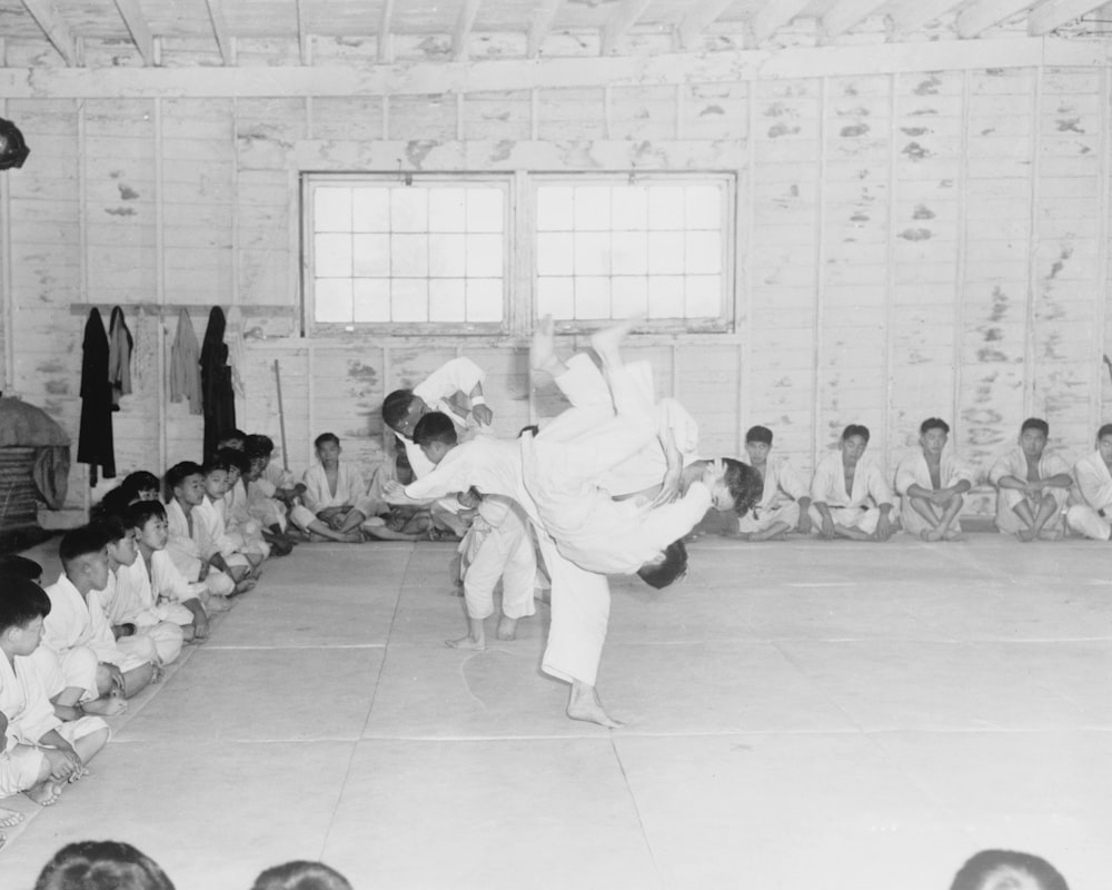 a group of young evacuees receiving instruction in Jiu Jitsui, or Judo wrestling at Portland (Oregon) Assembly Center, while the rest of class look on
