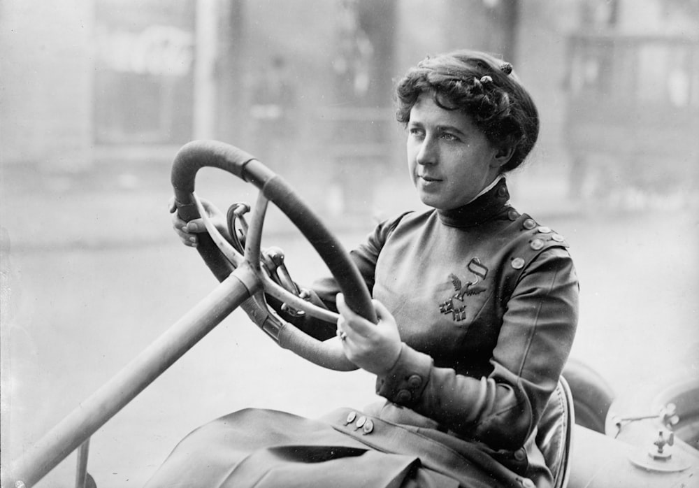 Race car driver Joan Newton Cuneo, seated in racing car, facing left