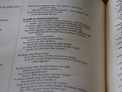 A close-up of an open book with text on both visible pages, showing a passage titled 'A call to lamentation'. The text describes religious themes and mentions rituals and offerings.