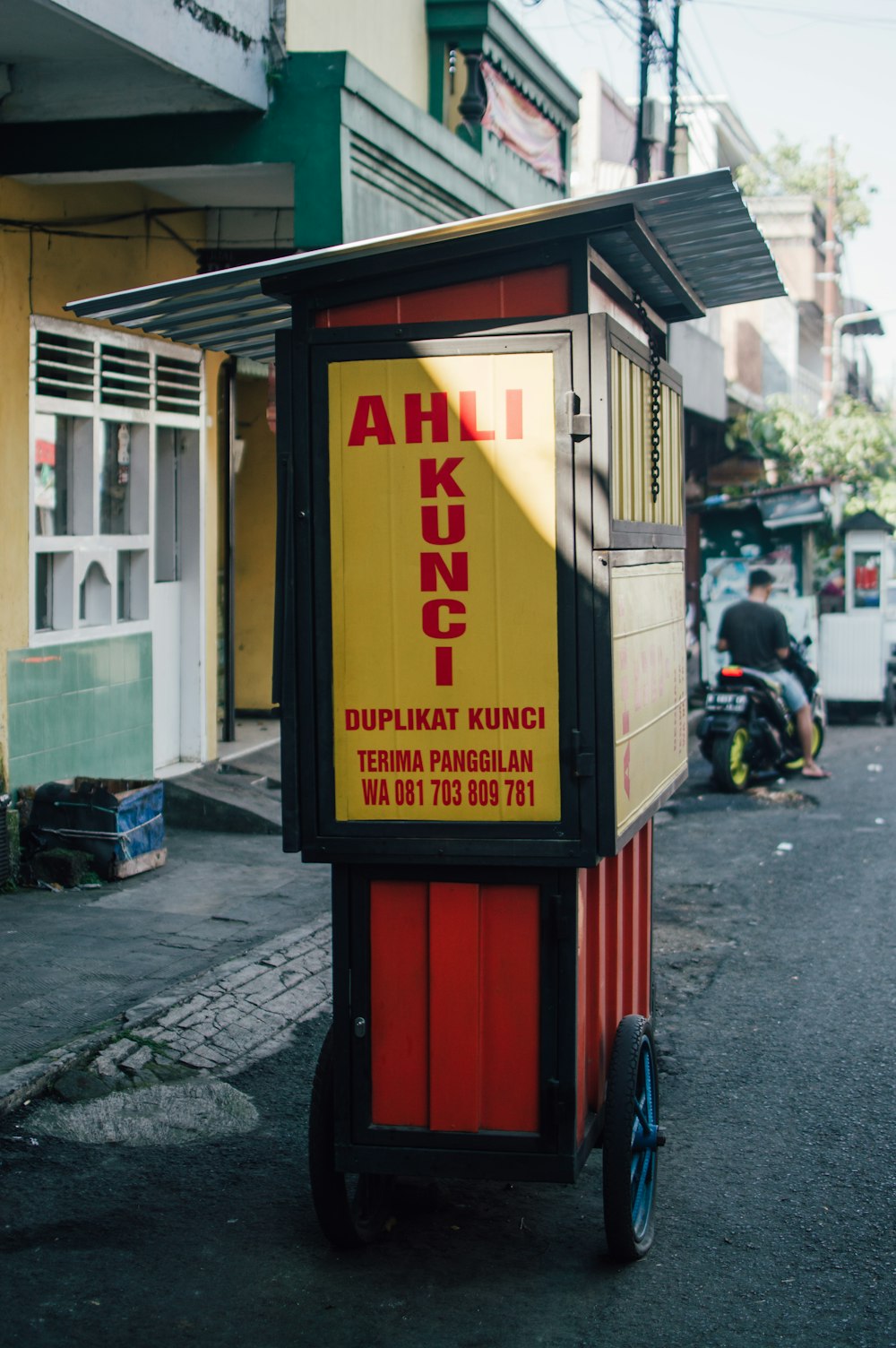 a red and yellow kiosk sitting on the side of a road