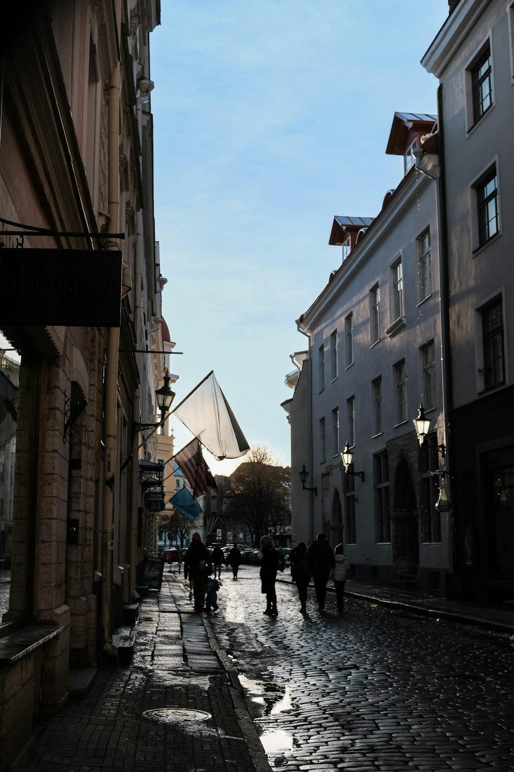 a group of people walking down a street next to tall buildings