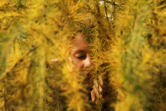 a woman hiding behind a tree with her eyes closed