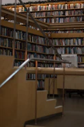 Wide shot of a cozy library room featuring built-in wooden bookshelves and warm lighting.