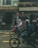 Several people wearing helmets are riding motorbikes along a street in front of a building with signs in Vietnamese. The atmosphere appears busy, with various shops and a hostel visible in the background.