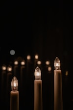 Softly lit candles in minimalist containers glowing warmly in an intimate event setting.