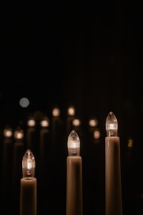 Softly lit candles in minimalist containers glowing warmly in an intimate event setting.