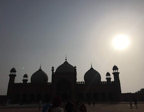 A serene view of pilgrims walking near a grand mosque during sunset.