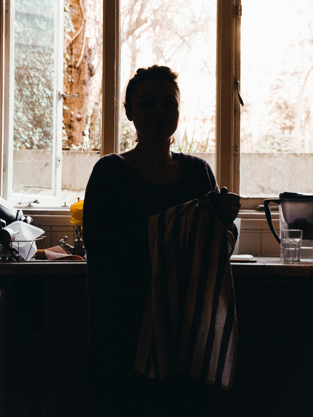 a woman standing in a kitchen holding a towel