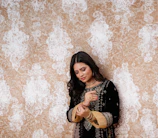 An elegant model wearing traditional gold rings against a deep charcoal background.