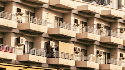 Technician repairing an air conditioning unit on a residential building balcony.