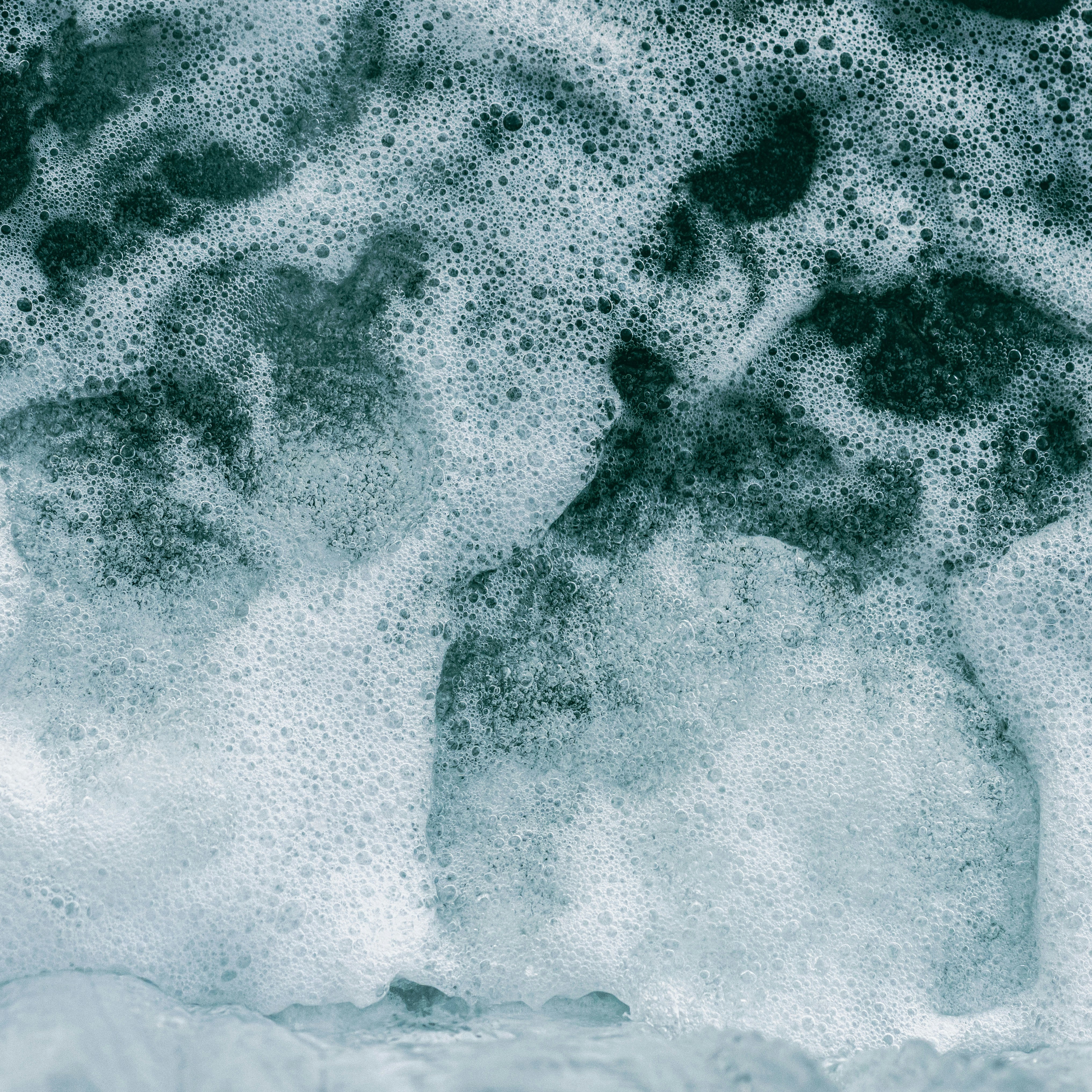 a person standing in a foamy area next to a surfboard