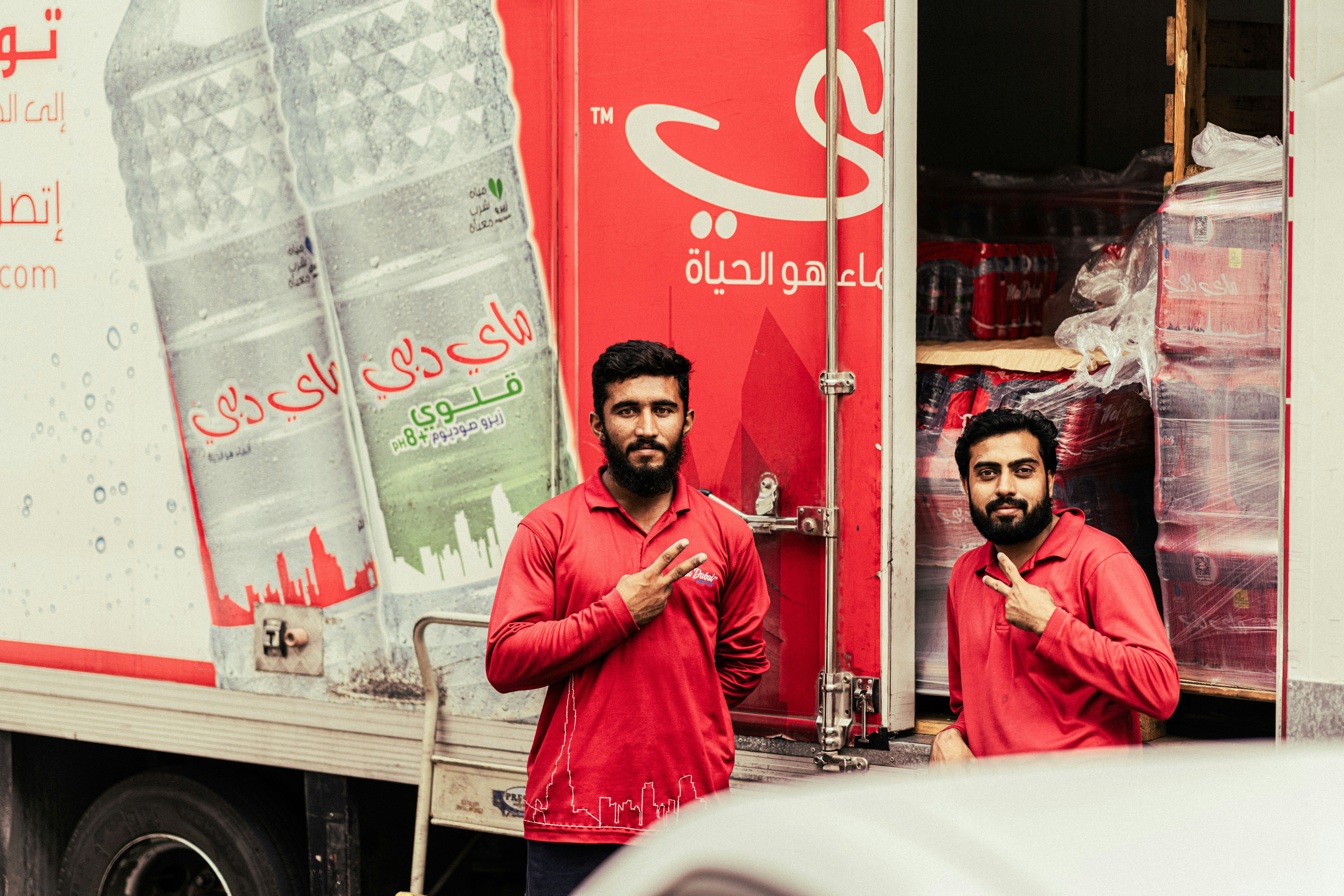 two men in red shirts standing next to a truck