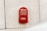 A bright red Emirates Post letter mailbox is mounted on a textured, off-white concrete wall. The surface of the wall is slightly stained near the bottom of the mailbox. Arabic and English text are clearly visible on the mailbox, along with the Emirates Post logo.
