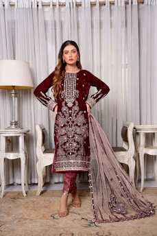 Elegant woman in a richly embroidered Kashmiri pheran standing against a warm ivory backdrop.