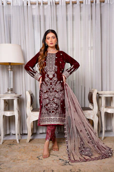 Elegant Iraqi woman in a flowing burgundy chomah dress standing gracefully against a soft ivory backdrop.