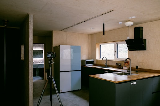 a kitchen with a sink a refrigerator and a tripod
