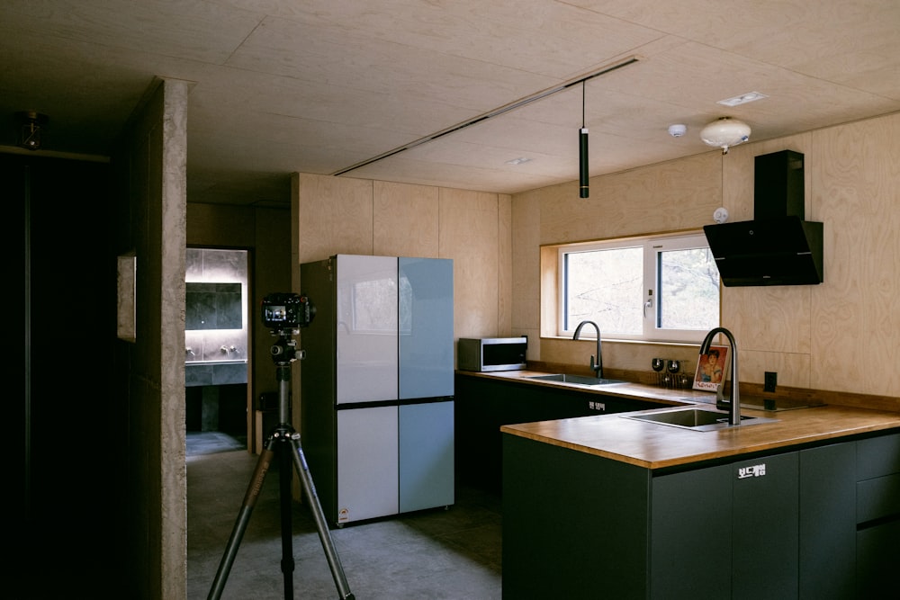 a kitchen with a sink a refrigerator and a tripod