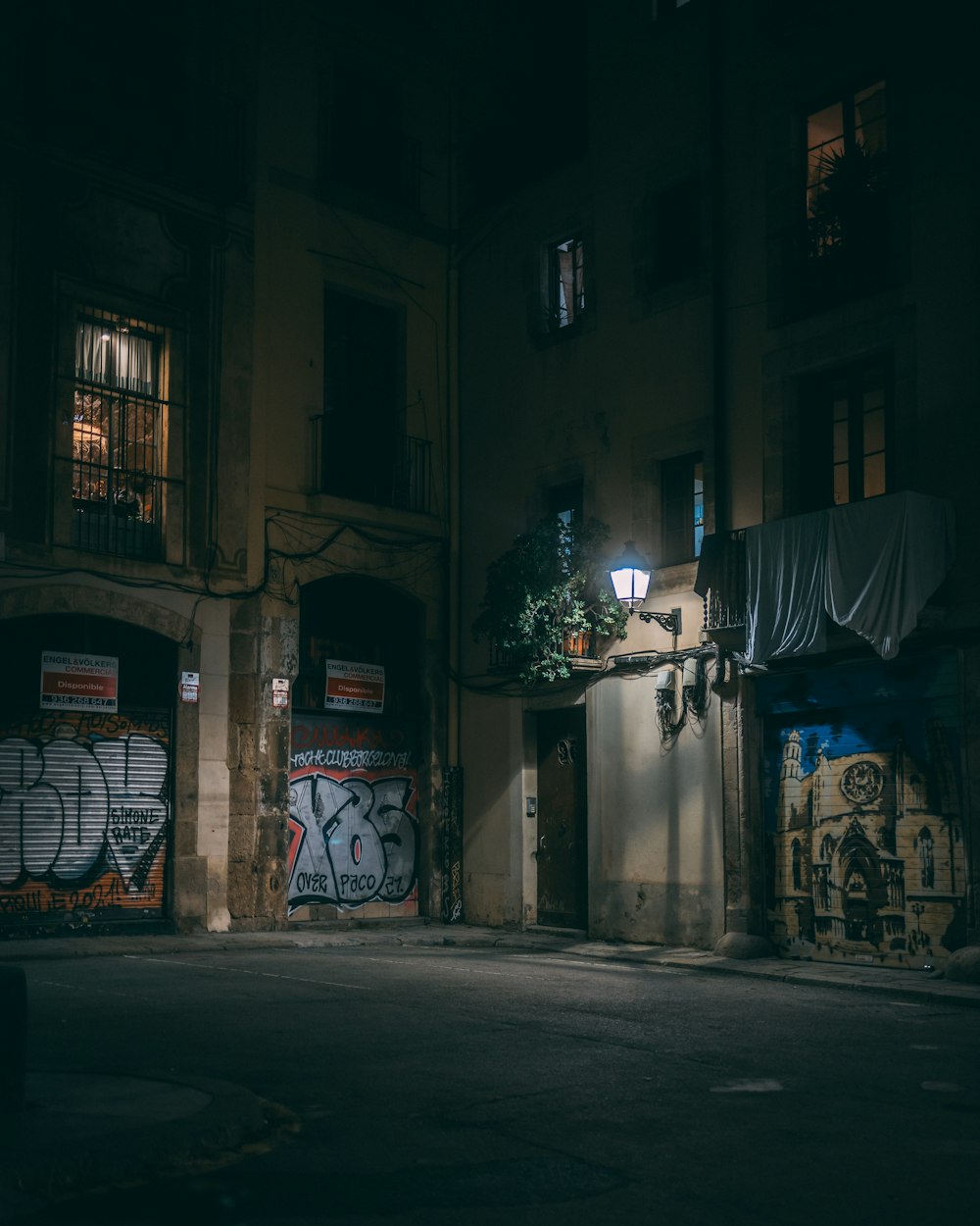 a dark street at night with graffiti on the buildings