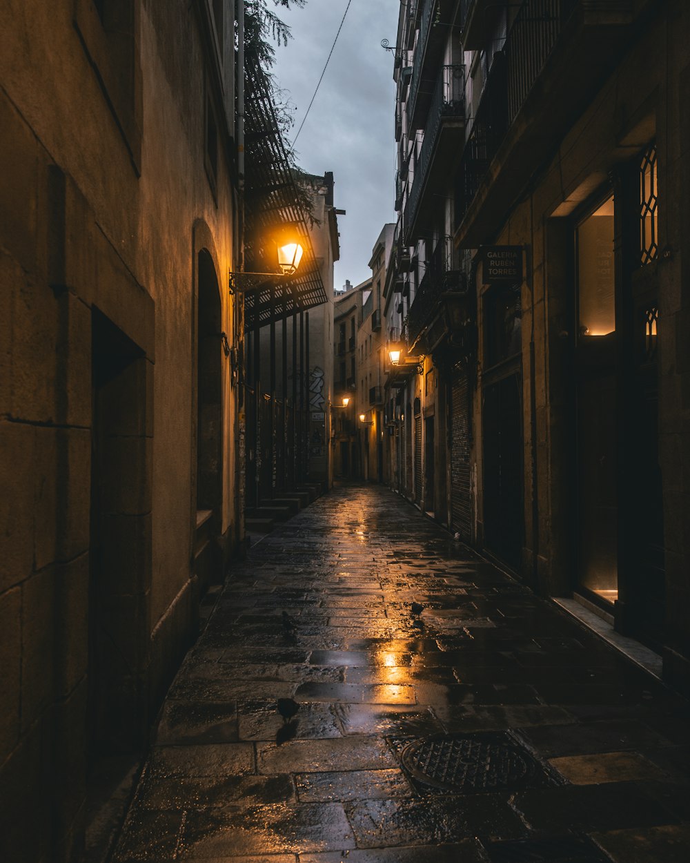 a dark alley way with a street lamp on a rainy night