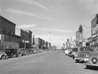 A sepia-toned historic photo of Enon Valley’s main street bustling with people and vintage cars.