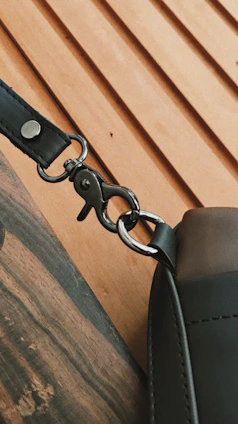 Side view of a charcoal leather strap showing supple grain and sleek hardware