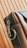 A close-up of a stylish leather bag with a metal zipper and a sturdy metal ring on its side. The bag's material appears smooth and high-quality, with careful stitching visible along the edges. The background features a wooden pattern with vertical lines.